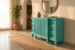 Turquoise sideboard in a sunlit entryway with mirror and plant