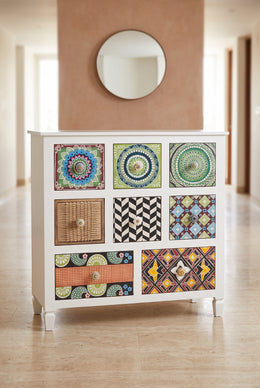 Tile print chest of drawers in a hallway below a round mirror